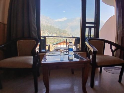 a room with two chairs and a table and a window at Hotel Cloud Height in Dharmsala