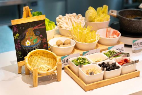a table topped with bowls of vegetables and a table with a table at Atour S Hotel Chengdu Taikoo Li in Chengdu