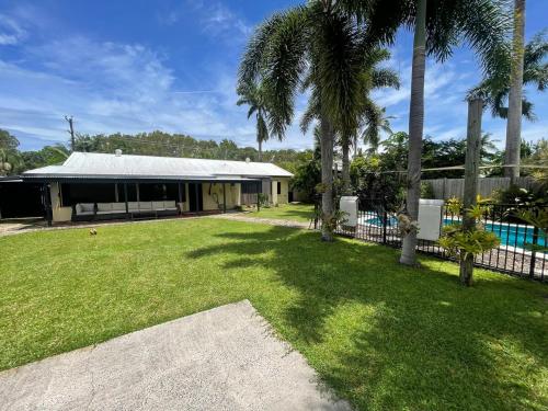 a house with a pool and a yard with palm trees at Tropical family beach house in Holloways Beach
