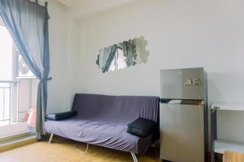 a purple couch in a room with a refrigerator at Cozy Stay 1BR at M-Town Signature Apartment By Travelio in Tangerang