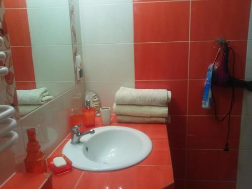 a bathroom with a white sink and red tiles at Kwatera Na Rogu in Augustów