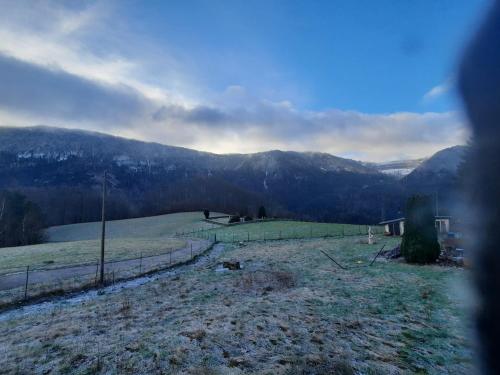 un campo con una valla y montañas al fondo en AirBee&Bee - Creux du Van, en Brot-Dessous