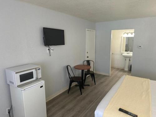 Kleines Zimmer mit einem Bett und einem Tisch mit einer Mikrowelle. in der Unterkunft Premier Inns Metro in Phoenix