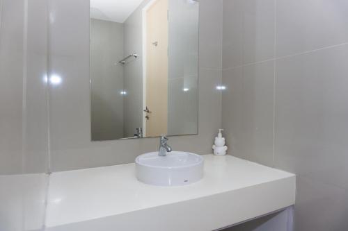 a white bathroom with a sink and a mirror at Cozy Living Studio Apartment Tree Park City BSD By Travelio in Tangerang
