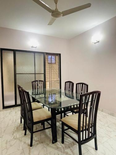 a dining room with a glass table and chairs at Uttara Luxury Apartment Near Airport & Metro in Dhaka