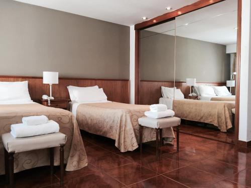 a hotel room with two beds and a mirror at Hotel Ortegal in Mar del Plata