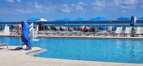 a swimming pool with chairs and blue umbrellas at Stunning Beachfront condo in sunny Sunny Isles Beach with AC, fitness room, WiFi in Sunny Isles Beach