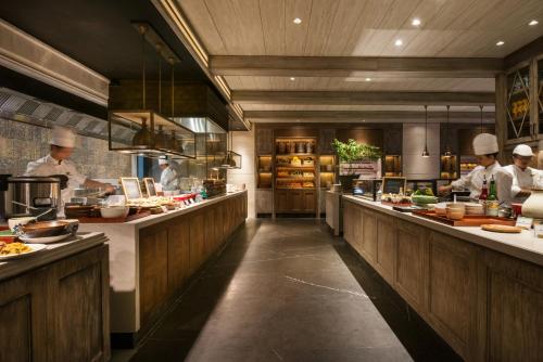 a kitchen with chefs preparing food in a restaurant at Keraton At The Plaza, part of The Unbound Collection by Hyatt in Jakarta