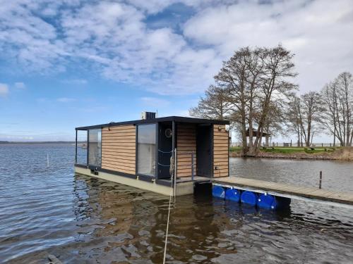 a tiny house on a dock on a body of water at Hausboot Am See Robert Döring in Riether Stiege