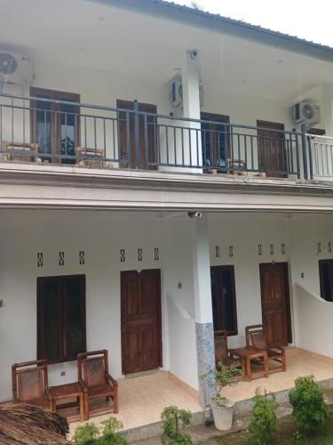 a building with wooden doors and chairs on it at Roby Homestay in Kuta Lombok