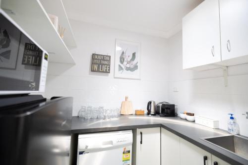 a kitchen with white cabinets and a counter top at Nu Leaf Retreat in Pokolbin