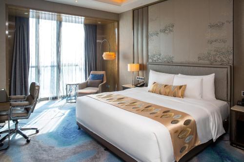a hotel room with a large bed and a desk at Pullman Yantai Center in Yantai