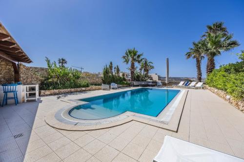 a swimming pool in a backyard with palm trees at Lilla Bo - Ocean View Villa in San Lawrenz