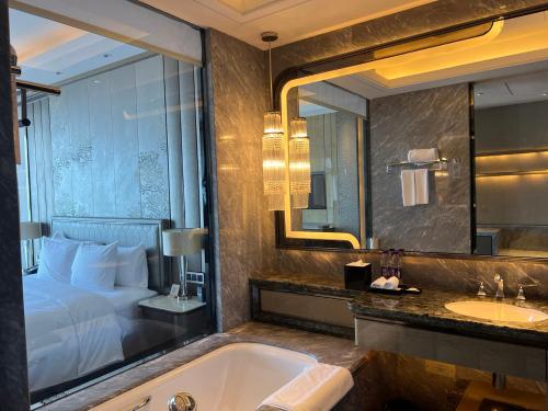 a bathroom with a tub and a bed and a sink at Pullman Yantai Center in Yantai