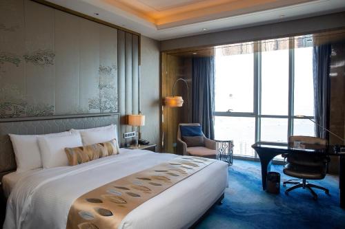a hotel room with a large bed and a desk at Pullman Yantai Center in Yantai