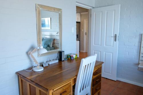 a wooden desk with a mirror and a white chair at Bayside Cottage in Cape Town