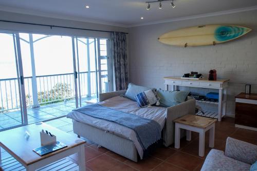 a living room with a couch and a surfboard on the wall at Bayside Cottage in Cape Town