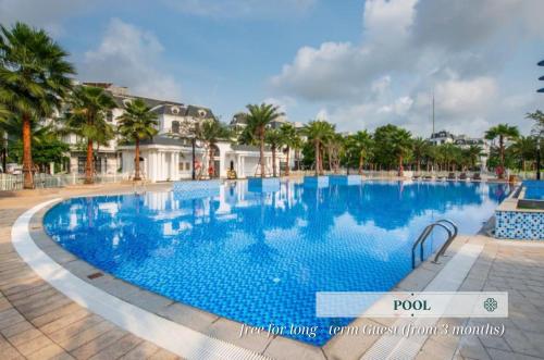 a large swimming pool in a resort with palm trees at Merci Vinhomes Imperia Hai Phong in Hai Phong