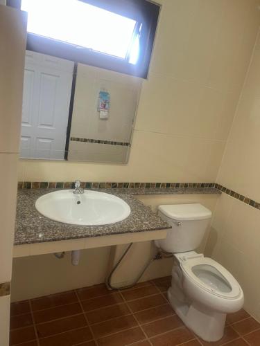 a bathroom with a sink and a toilet and a mirror at บ้านสวนรัญจวนสาขาสุราษฎร์ธานี in Ban Huai Chiat