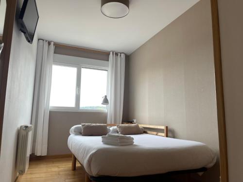 a bedroom with a bed with white sheets and a window at Pension 23-Vinte e Tres in O Pedrouzo
