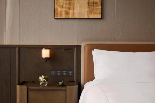 a bedroom with a bed and a nightstand with a white bedspread at Conrad Chongqing - Indulge in the magical 8D city landscape in Chongqing