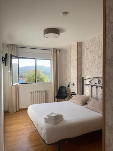 a bedroom with a large white bed with a window at Pension 23-Vinte e Tres in O Pedrouzo