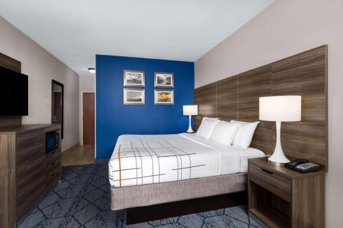 a hotel room with a bed and a blue wall at La Quinta by Wyndham Denton - University Drive in Denton