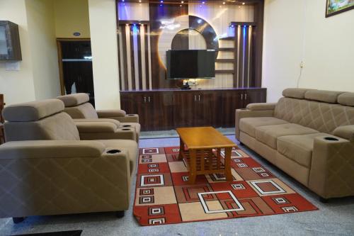 a waiting room with couches and a table and a tv at TIRUMALA PREMIUM HOME STAY in Tirupati