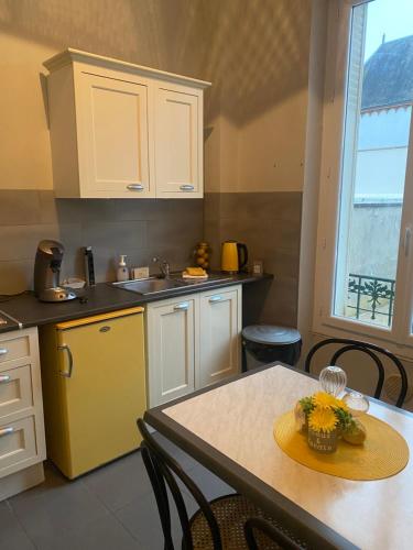 Il comprend une cuisine équipée d'une table et d'un réfrigérateur jaune. dans l'établissement Tranquillité en Ville, à Vierzon