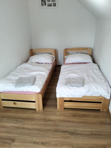 two beds sitting next to each other in a room at Noclegi i sauna w starym domu in Pławnica