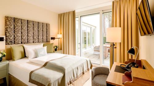a bedroom with a bed and a desk and a window at Parkhotel Rothof in Munich
