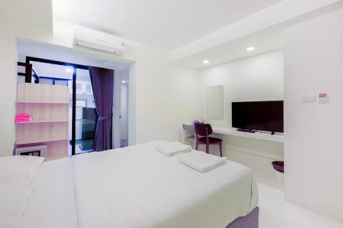 a white bedroom with a bed and a tv at Quite Grove Hotel in Bangkok