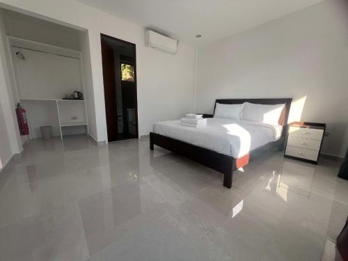 a white bedroom with a bed and a night stand at Viva La Rosa Hometel in Anda