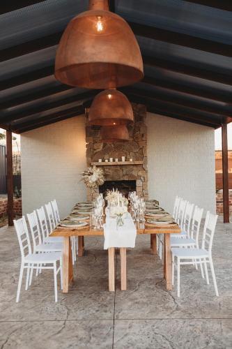 a wooden table with white chairs and a fireplace at Wagga Wagga Country Cottages in Wagga Wagga