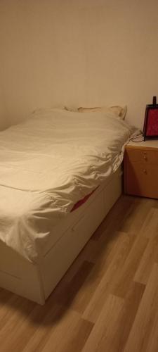 un lit défait dans une chambre avec un plancher en bois dans l'établissement Maison calme, à Payrin-Augmontel