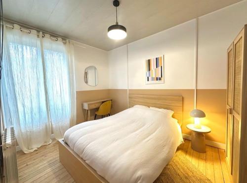 une chambre avec un grand lit blanc et un bureau dans l'établissement Mexico, appartement décoré avec goût, à Reims