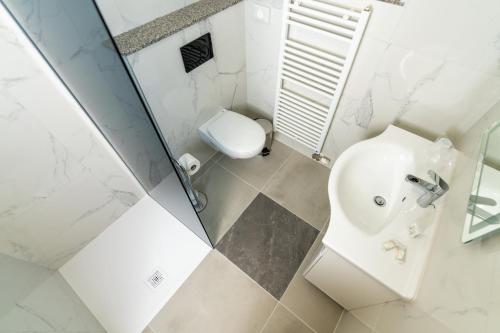 a white bathroom with a toilet and a sink at Hotel Center Bohinjsko Jezero in Bohinj
