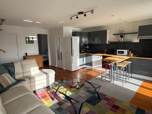 a living room with a white couch and a kitchen at Duplex vue mer, centre ville in Royan