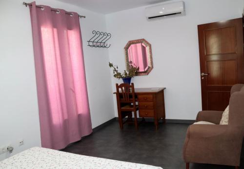 sypialnia z różowymi zasłonami, krzesłem i lustrem w obiekcie Casa llena de vida con patio y terraza w mieście Coín