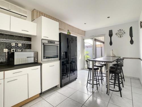 une cuisine avec des armoires blanches et une table avec des chaises dans l'établissement Villa Dedele, à Soustons