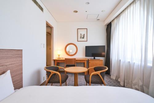 a hotel room with a bed and a table and chairs at Mito Sannomaru Hotel in Mito