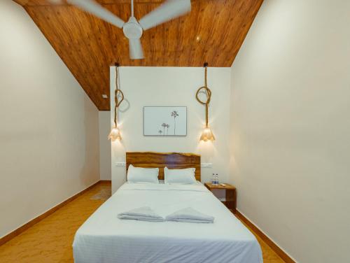 a bedroom with a white bed with a wooden ceiling at Sunset Cafe Beach Stay in Gokarna