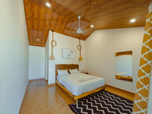 a bedroom with a bed and a wooden ceiling at Sunset Cafe Beach Stay in Gokarna