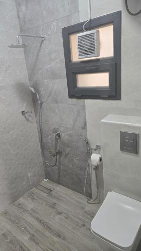 a bathroom with a shower with a toilet and a window at Roghan Hospitality Inn in Al Ḩamrāʼ