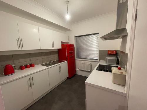 cocina con nevera roja y armarios blancos en Stylish 1 bedroom Flat Brixton, en Londres