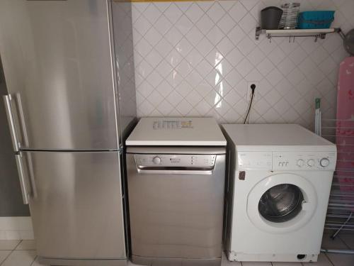 a kitchen with a refrigerator and a washing machine at Le gîte de l'Ecurie des 3 Châteaux in La Sauve-Majeure