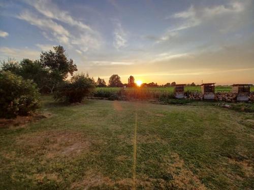 a field with the sun setting in the distance at Le gîte de l'Ecurie des 3 Châteaux in La Sauve-Majeure
