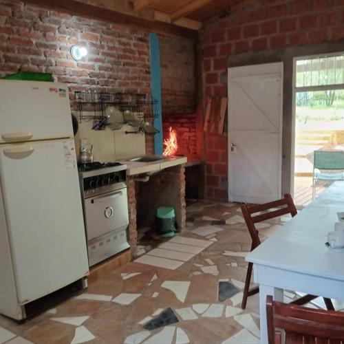 a kitchen with a white refrigerator and a brick wall at Cabaña el bananal in Profundidad
