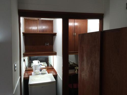 a small kitchen with wooden cabinets and a refrigerator at London Continental Hotel in London