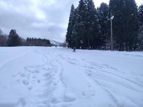 a person is skiing down a snow covered road at BBQ 夏季プール マッサージチェア 舞子スノーリゾート 加賀屋旅館 南魚沼 Kagaya Ryokan 加贺屋旅馆 in Minami Uonuma